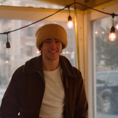 A portrait of Cameron Winter beneath hanging string lights