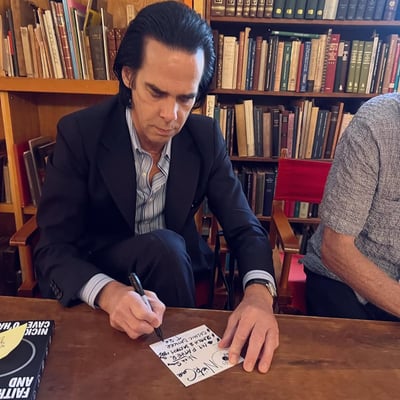 An artist filling in a Songs That Found Me card at a signing table