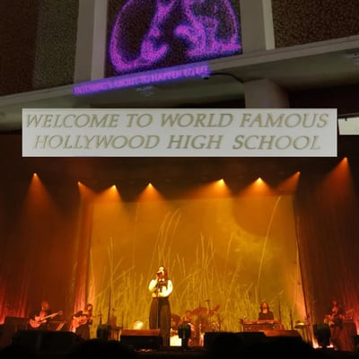 A lit school auditorium stage beneath a Welcome to World Famous Hollywood High School sign