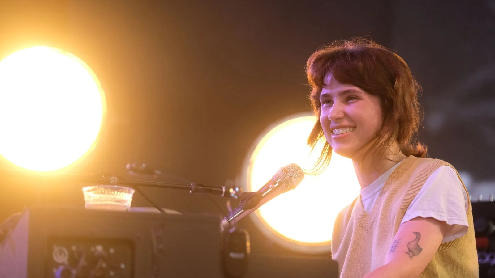 A musician singing into a microphone, lit from behind