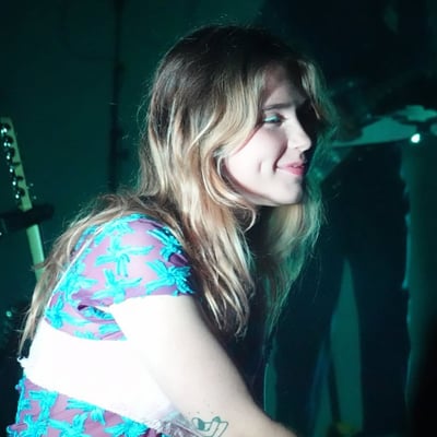 A singer lit in teal, mid-song